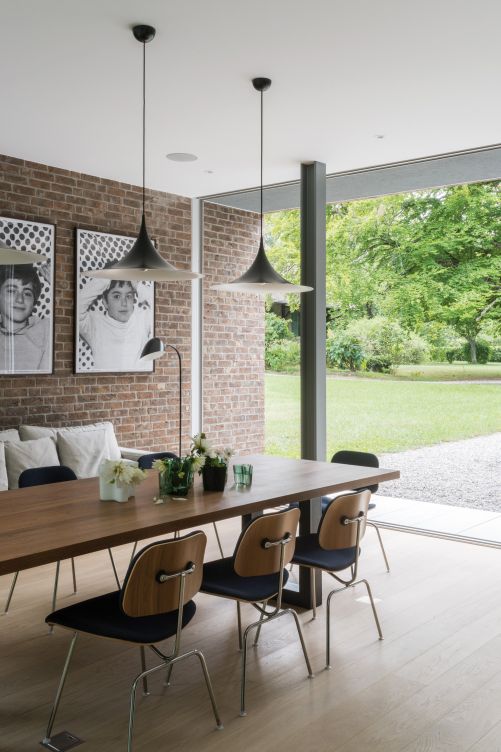 Über dem Esstisch nach Mass hängen Pendelleuchten «Semi» von Gubi, daneben Eames-Stühle «LCM» von Vitra.
