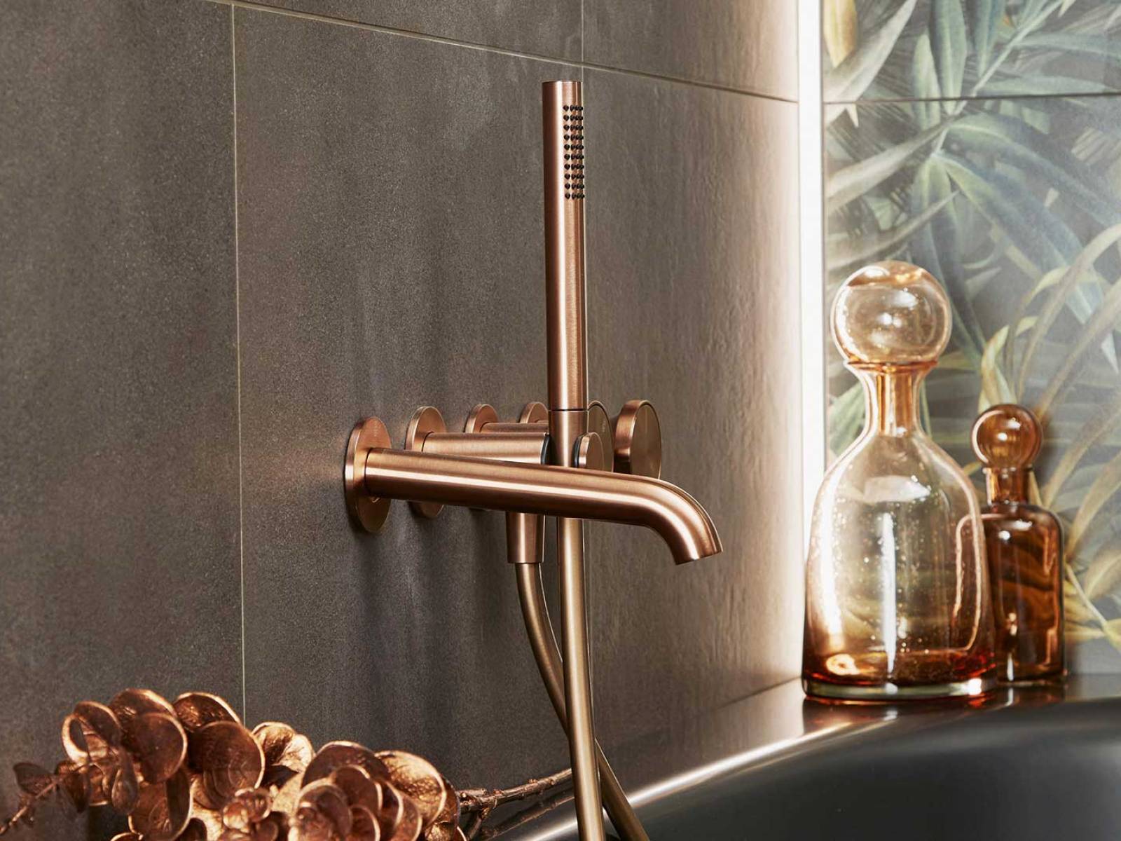 Dieses Badezimmer verströmt eine glamouröse, verspielte Ästhetik mit modernem Ambiente. Armaturen aus gebürstetem Kupfer schaffen ein luxuriöses Flair. Dunkle Töne und natürliche Holzelemente ergänzen die exotisch inspirierte Wandgestaltung zu einem Wohlfühlraum aus hochwertigem Materialmix und liebevollen Details. SABAG.