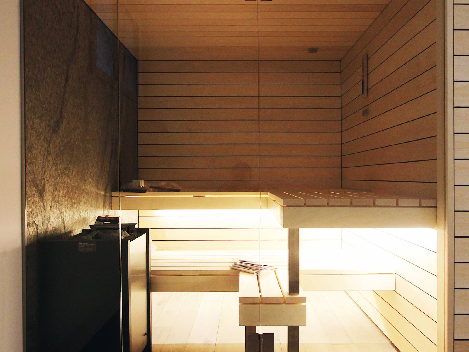 Espenholz, Glas und Naturstein; die Bio-Sauna des Schweizer Herstellers kann sich sehen lassen. Aber auch technisch hat sie mit biologischem Raumklima, Farb­lichttherapie und Kräuterdampfquelle einiges vorzuweisen. Ging.