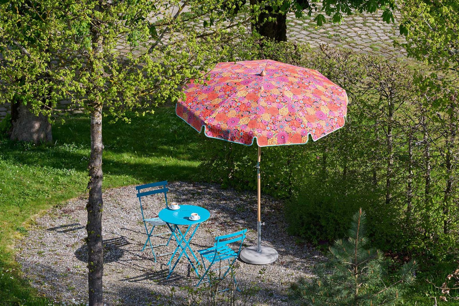 Unter dem an einen Blumentanz erinnernden Stoffdesign «Enchanted Magenta» von Kaffe Fassett blüht der Sonnenschirm «Alexo» von 1931 auf. glatz.com